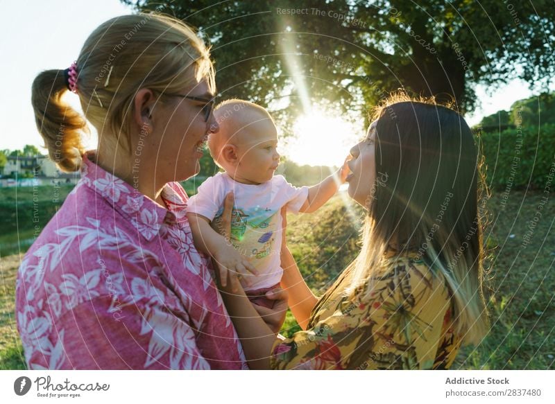 Glückliches lesbisches Paar mit Kind Mutter Park grün Sonnenstrahlen Mensch Frau Fröhlichkeit Sommer Lifestyle Liebe gleichgeschlechtliche Eltern Homosexualität