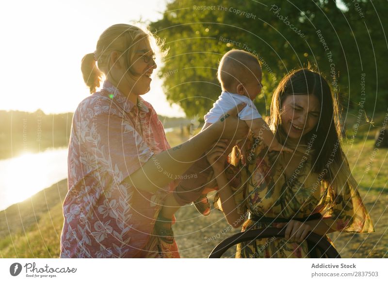 Glückliche Familie mit Kind Mutter Park grün tragen Sonnenstrahlen Mensch Frau Fröhlichkeit Sommer Lifestyle Liebe gleichgeschlechtliche Eltern Homosexualität