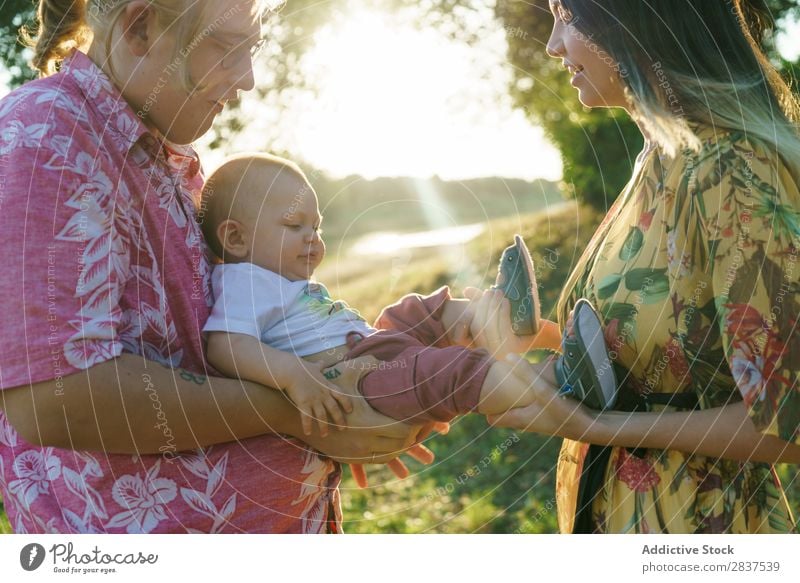 Glückliches lesbisches Paar mit Kind Mutter Park grün Sonnenstrahlen Mensch Frau Fröhlichkeit Sommer Lifestyle Liebe gleichgeschlechtliche Eltern Homosexualität