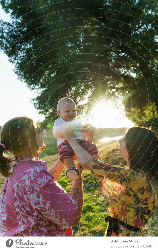 Glückliches lesbisches Paar mit Kind Mutter Park grün Sonnenstrahlen Mensch Frau Fröhlichkeit Sommer Lifestyle Liebe gleichgeschlechtliche Eltern Homosexualität