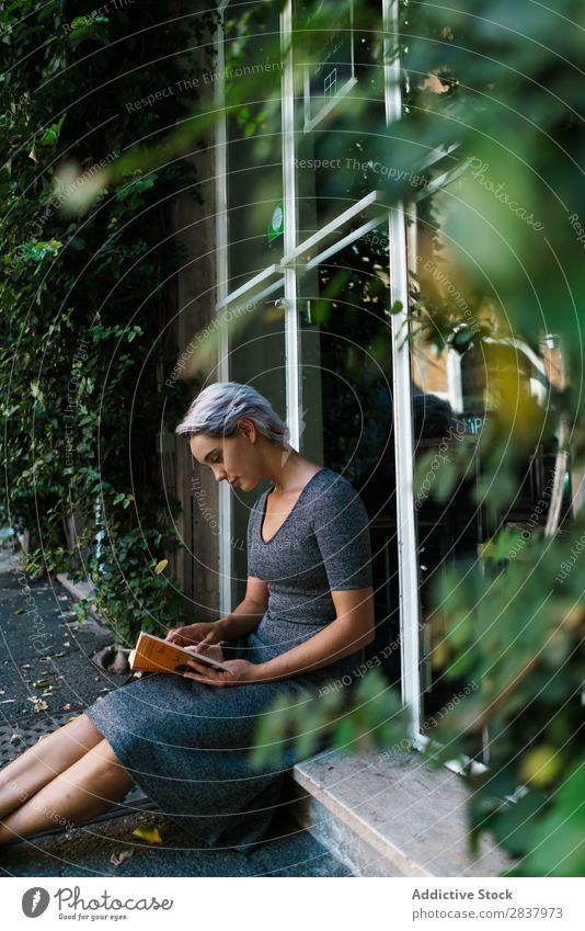 Frau liest Buch am Fenster Straße sitzen Fenstersims schön Mädchen Jugendliche Schüler hübsch Erwachsene Lächeln Großstadt Beautyfotografie attraktiv lässig