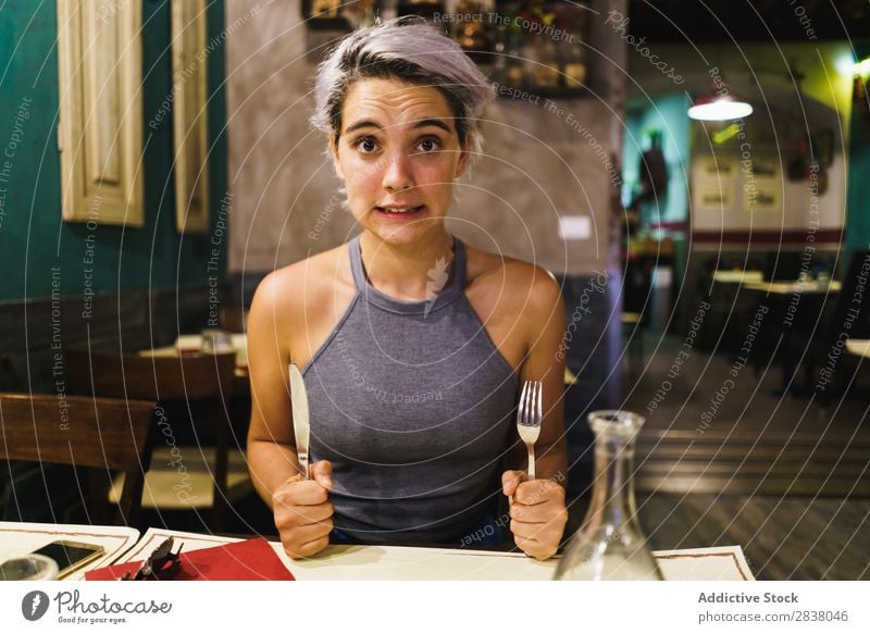 Wütendes Mädchen, das mit Silberwaren posiert. Frau Restaurant Appetit & Hunger Spaß haben Ausdruck Gesichtsbehandlung Gefühle humorvoll hysterisch Wut Café