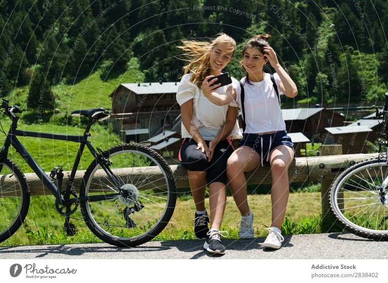 Frauen mit Fahrrädern, die einen Selfie machen. sitzen Zaun PDA Browsen sportlich Fahrrad Freundschaft Sport Zyklus Mädchen Aktion Lifestyle Fahrradfahren