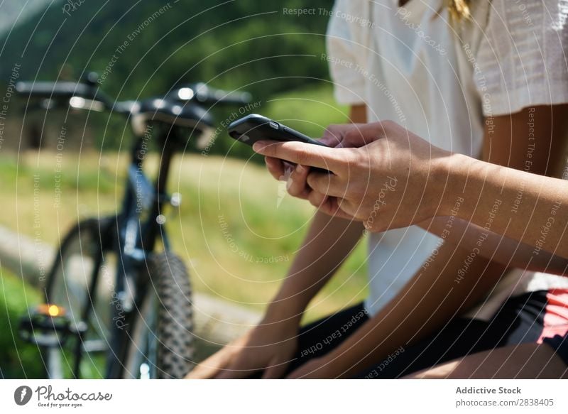 Schneiden Sie Frauen mit Fahrrädern, die auf dem Smartphone surfen. sitzen Zaun PDA Browsen sportlich Fahrrad Freundschaft Sport Zyklus Mädchen Aktion Lifestyle