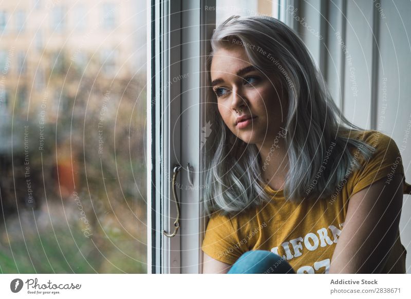 Nachdenkliche blonde Frau am Fenster hübsch heimwärts Jugendliche sitzen Fürsorge aussruhen schön Lifestyle Beautyfotografie attraktiv Wegsehen Porträt Dame