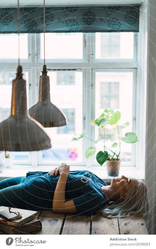 Lächelnde Frau auf dem Tisch liegend hübsch heimwärts Jugendliche blond schön lügen Holz Lifestyle Beautyfotografie attraktiv Porträt Dame Raum Mensch Erholung