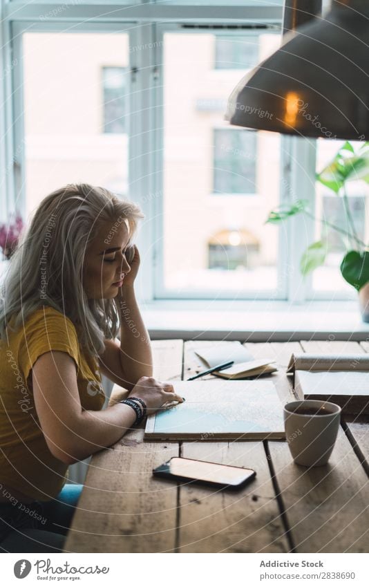 Frau mit Buch bei Tisch hübsch heimwärts Jugendliche blond besinnlich Denken sitzen Landkarte Wege & Pfade schön Lifestyle Beautyfotografie attraktiv Porträt