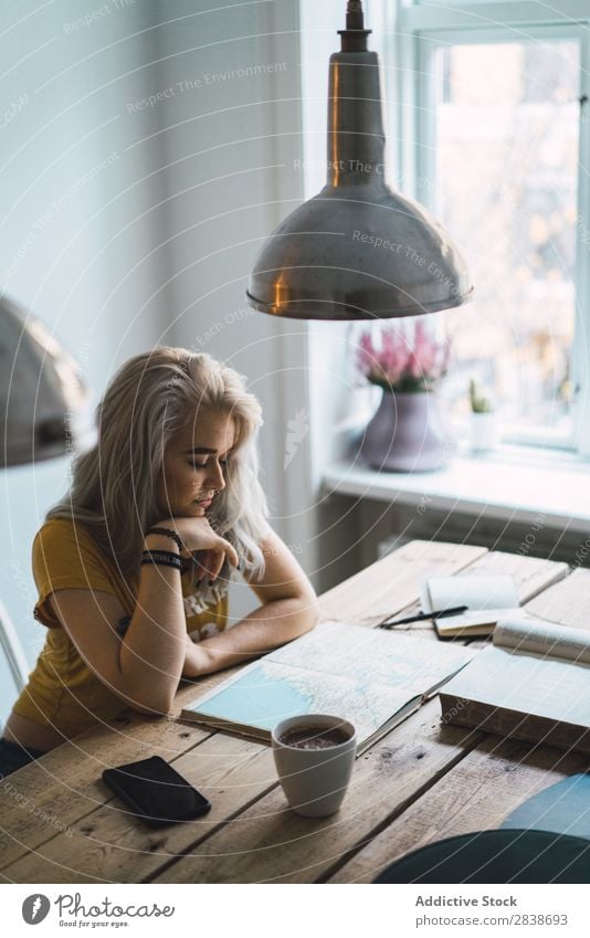 Frau mit Buch bei Tisch hübsch heimwärts Jugendliche blond besinnlich Denken sitzen Landkarte Wege & Pfade schön Lifestyle Beautyfotografie attraktiv Porträt