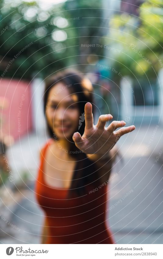 Fröhliche Frau mit Gestenstopp hübsch asiatisch Jugendliche Lächeln versteckend stoppen gestikulieren Blick in die Kamera Straße Stadt schön Porträt attraktiv