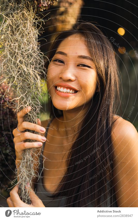 Fröhliche Frau mit trockenem Gras hübsch asiatisch Jugendliche regenarm Behaarung Körperhaltung heiter Lächeln schön Porträt attraktiv Beautyfotografie Mensch