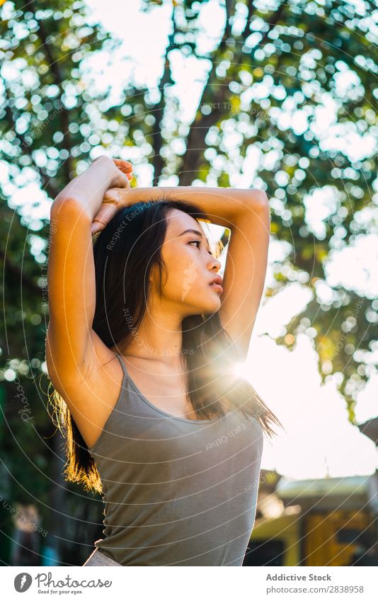 Fröhliche asiatische Frau mit brünetten Haaren hübsch Jugendliche heiter Lächeln Glück Haltehaar Freude Park Stadt schön Porträt attraktiv Beautyfotografie