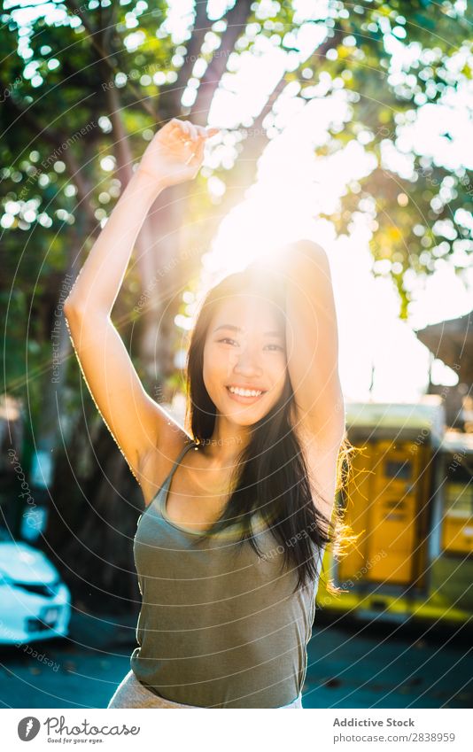 Fröhliche asiatische Frau mit brünetten Haaren hübsch Jugendliche heiter Lächeln Glück Haltehaar Freude Park Stadt schön Porträt attraktiv Beautyfotografie