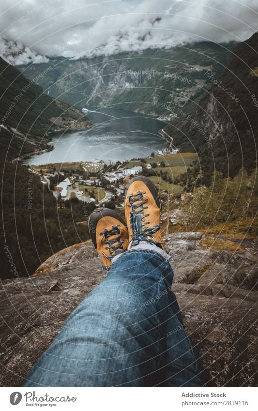 Getreideperson, die auf einer Klippe sitzt. Mensch Reisender Natur Ferien & Urlaub & Reisen Geirangerfjord Landschaft Aussicht Wohnsiedlung Tourismus Beine