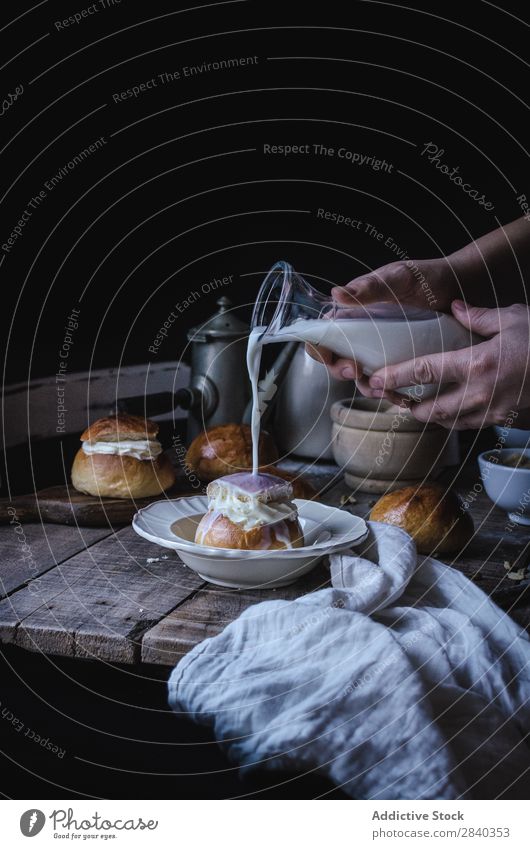 Hände gießen Milch auf Brötchen süß Backwaren rustikal lecker Hand Gießen Creme Portion Dessert Lebensmittel frisch geschmackvoll gebastelt Feinschmecker