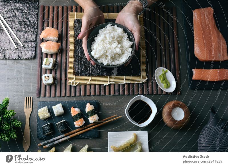 Frau bereitet zu Hause Sushi-Rollen zu. machen Hand Lebensmittel Reis vorbereitend Vorbereitung maki Essstäbchen Orientalisch Essen zubereiten Unterlage Seegras