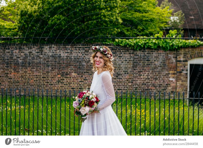 Hübsche Frau mit Kranz am Zaun Braut Kittel weiß Kränze Girlande Grabkränze Blume Haufen Blumenstrauß laufen Imkerschleier Kopfschmuck elegant Kleid