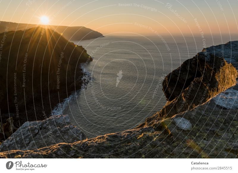 Auf und Untergänge. Auf der Klippe am Strand sieht man die Sonne untergehen Natur Landschaft Urelemente Wolkenloser Himmel Horizont Schönes Wetter Felsen Wellen