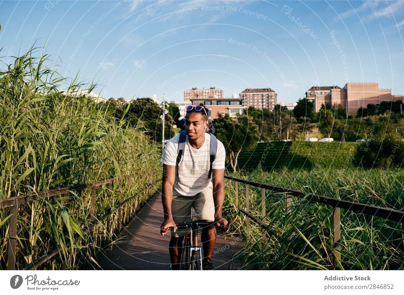 Junger Mann fährt Fahrrad auf dem Bürgersteig Straßenbelag Reiten Gras Brücke Geländer Lifestyle Verkehr Stadt Zyklus Großstadt Aktion Gasse Motorradfahren