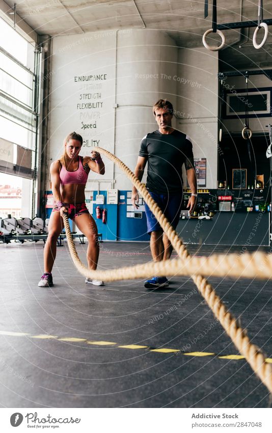 Frau trainiert mit Seilen ausarbeitend Trainerin Sporthalle Fitness Schiffstau Bodybuilder Gerät in Bewegung Training üben Kraft Ausbilderin Aktion Tatkraft