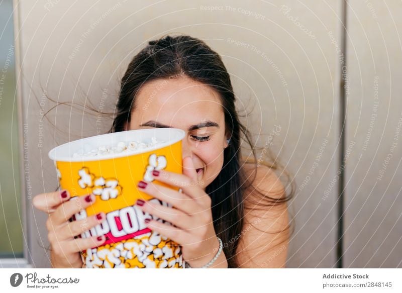 Hübsches Mädchen, das mit Popcorn posiert. Frau Youngster Popkorn lachen Freude Stadt heiter Eimer spielerisch Schickimicki Stil Bekleidung Porträt Deckfläche