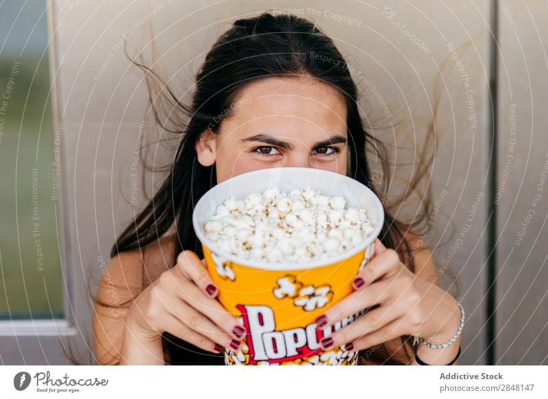 Hübsches Mädchen, das mit Popcorn posiert. Frau Youngster Popkorn lachen Freude Stadt heiter Eimer spielerisch Schickimicki Stil Bekleidung Porträt Deckfläche