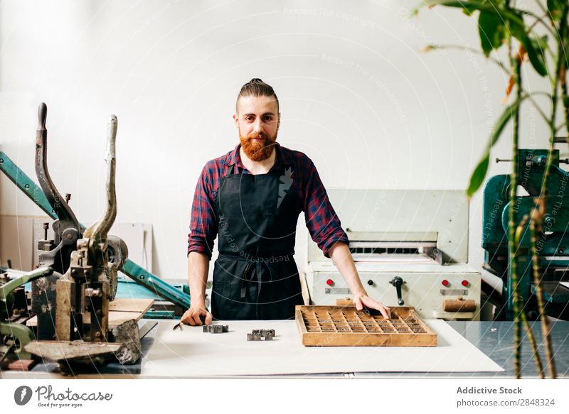 Bärtiger Mann in der Druckerei Typographie Arbeitsbereich Körperhaltung Ausdruck Buchmacherei Techniker selbstbewußt Handarbeit Brief Buchdruck Handwerkskunst