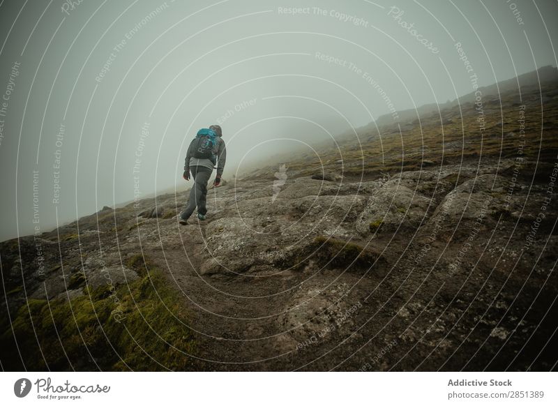 Mann, der auf einem felsigen, grünen Hang des Hügels geht. Landschaft Felsen Wildnis Tal Nebel Berghang Berge u. Gebirge Ferien & Urlaub & Reisen Wetter ruhig