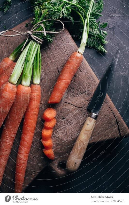 Frische Karotten in einem Holzschneidebrett Hintergrundbild Bündel Möhre mehrfarbig dunkel Lebensmittel frisch Ernte Gesundheit Messer Metall Ernährung Orange