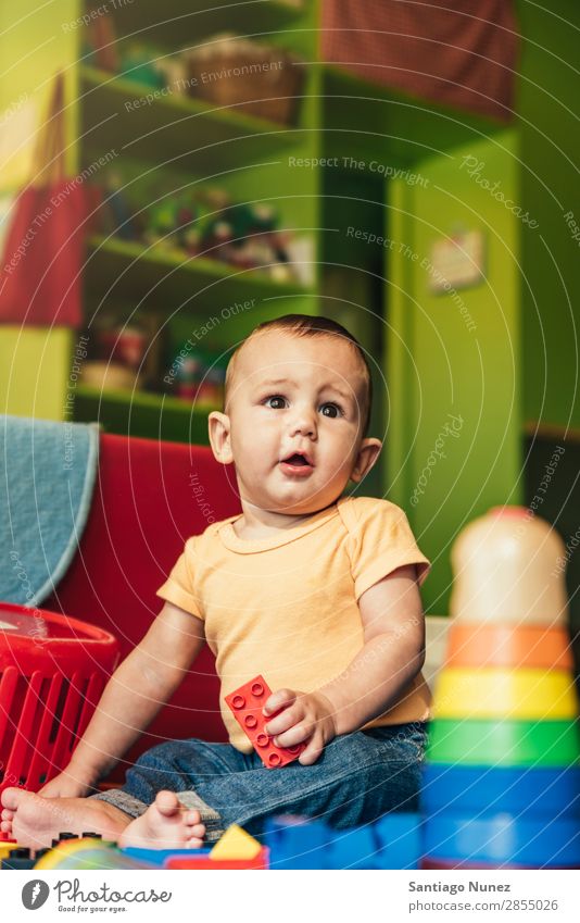 Frohes Baby beim Spielen mit Spielzeugblöcken. Kinderbetreuung Kindergarten Schule Kleinkind Junge klein LEGO Glück Fürsorge Etage niedlich Freude Vorschule