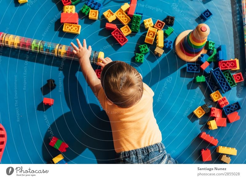 Frohes Baby beim Spielen mit Spielzeugblöcken. Kinderbetreuung Kindergarten Schule Kleinkind Junge klein LEGO Glück Fürsorge Etage niedlich Freude Vorschule