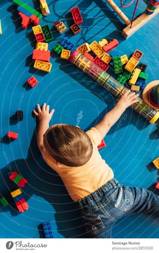 Frohes Baby beim Spielen mit Spielzeugblöcken. Kinderbetreuung Kindergarten Schule Kleinkind Junge klein LEGO Glück Fürsorge Etage niedlich Freude Vorschule