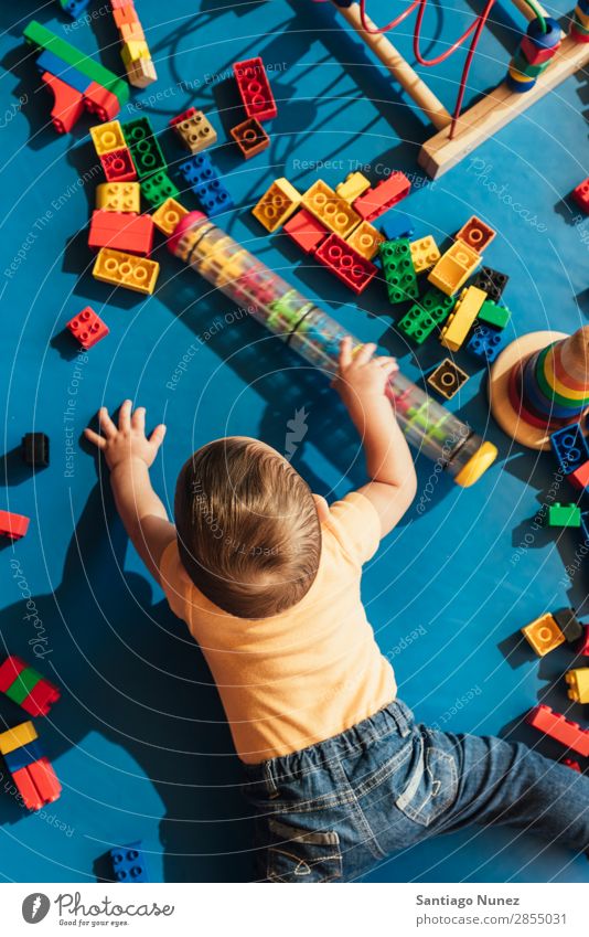 Frohes Baby beim Spielen mit Spielzeugblöcken. Kinderbetreuung Kindergarten Schule Kleinkind Junge klein Glück Fürsorge Etage niedlich Freude Vorschule Bildung