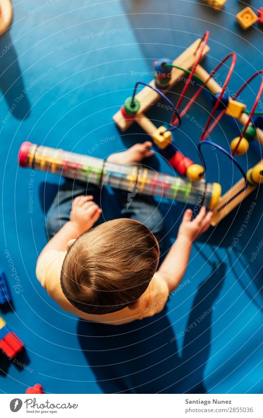 Frohes Baby beim Spielen mit Spielzeugblöcken. Kinderbetreuung Kindergarten Schule Kleinkind Junge klein Glück Fürsorge Etage niedlich Freude Vorschule Bildung