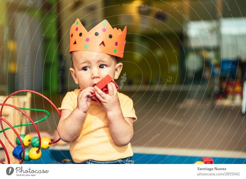 Frohes Baby beim Spielen mit Spielzeugblöcken. Kinderbetreuung Kindergarten Schule Krone König beißen Kleinkind Junge klein Glück Fürsorge Etage Porträt