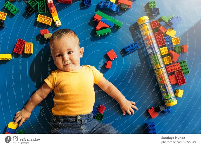 Frohes Baby beim Spielen mit Spielzeugblöcken. Kinderbetreuung Kindergarten Schule Kleinkind Junge klein Blöcke Glück Fürsorge Etage niedlich Freude Vorschule