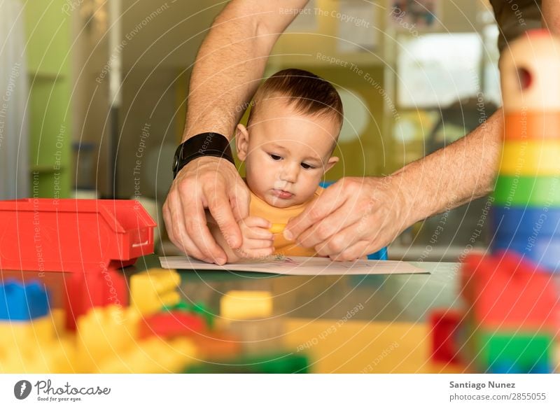 Kleinkind und Vater zeichnen auf einem Papier. Baby Spielen Kinderbetreuung Kindergarten Lehre Schule Papa Familie & Verwandtschaft lernen malen Spielzeug Farbe