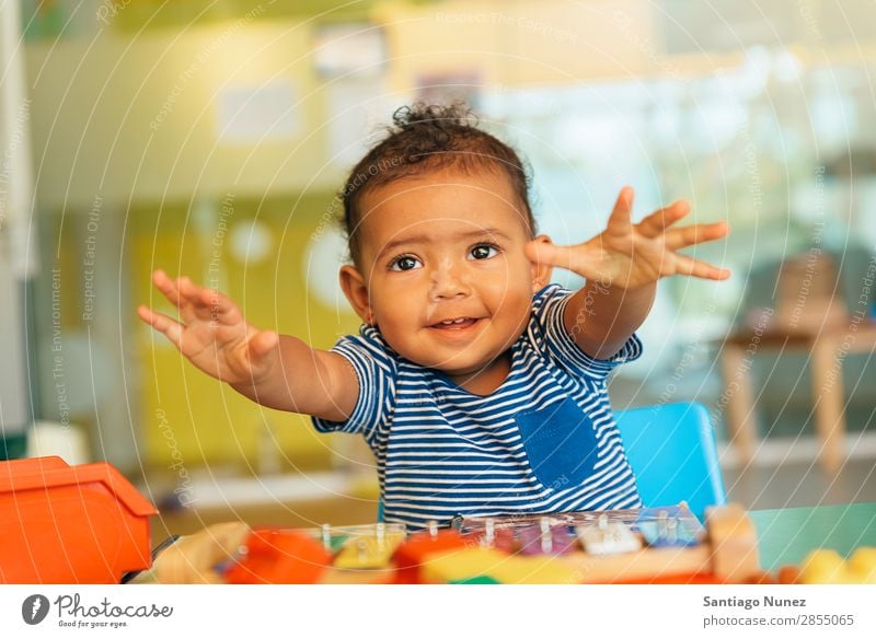 Frohes Baby beim Spielen mit Spielzeugblöcken. Kinderbetreuung Kindergarten Schule Kleinkind Mädchen klein Blöcke Lächeln Glück Fürsorge niedlich Umarmen