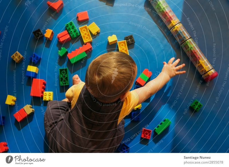 Frohes Baby beim Spielen mit Spielzeugblöcken. Kinderbetreuung Kindergarten Schule Kleinkind Junge klein LEGO Glück Fürsorge Etage niedlich Freude Vorschule