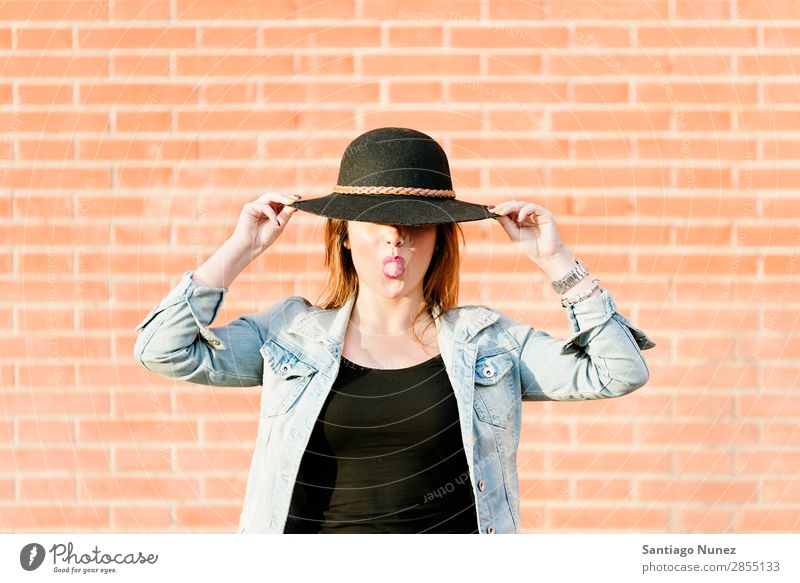 Blonder Hipster mit Strohhut auf orangem Ziegelgrund. Mode Wand Mädchen trendy Frau Jugendliche Schickimicki lässig Backstein Hintergrundbild Stil Porträt blond