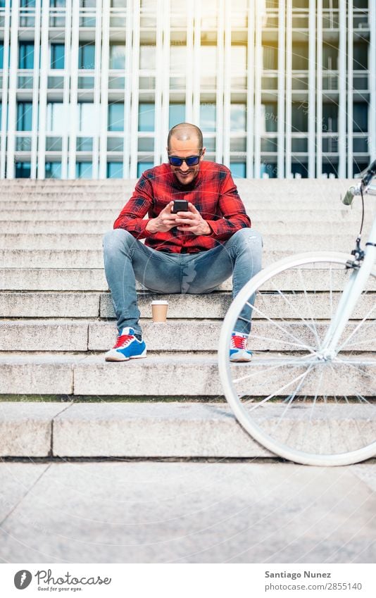 Junger Mann mit Handy und festem Fahrrad. Mobile Fixie Telefon Schickimicki Lifestyle stehen Fahrradfahren Großstadt Gebäude Solarzelle Stadt Mensch