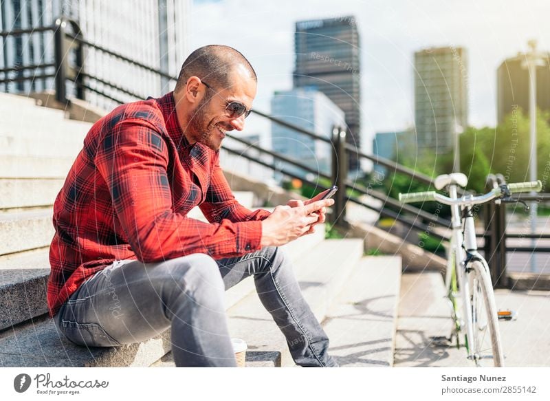 Junger Mann mit Handy und festem Fahrrad. Mobile Fixie Telefon Schickimicki Lifestyle stehen Fahrradfahren Großstadt Gebäude Solarzelle Stadt Mensch