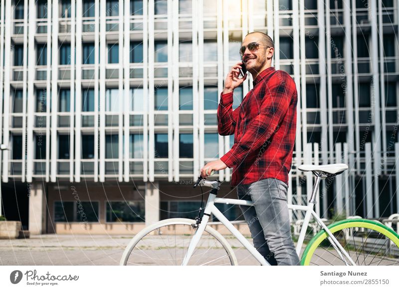 Junger Mann mit Handy und festem Fahrrad. Mobile Fixie Telefon Schickimicki Lifestyle stehen Fahrradfahren Großstadt Gebäude Solarzelle Stadt Mensch