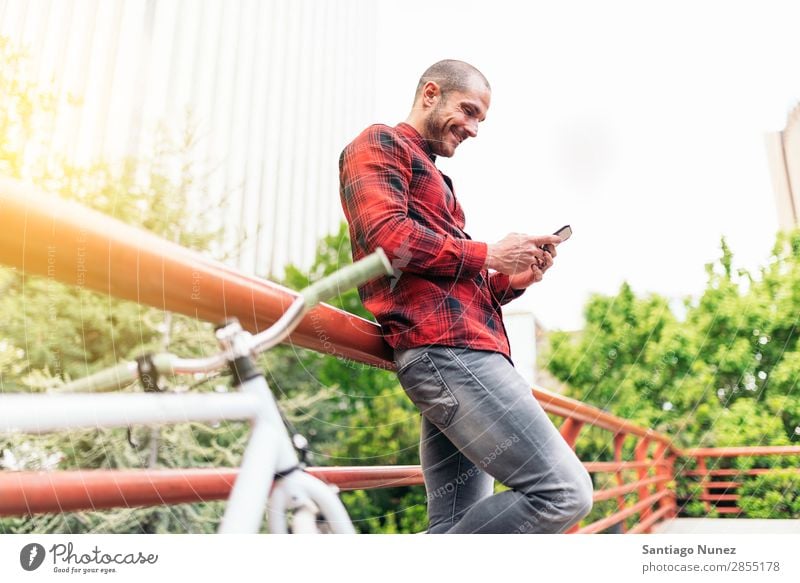 Junger Mann mit Handy und festem Fahrrad. Mobile Fixie Telefon Schickimicki Lifestyle stehen Fahrradfahren Großstadt Gebäude Solarzelle Stadt Mensch