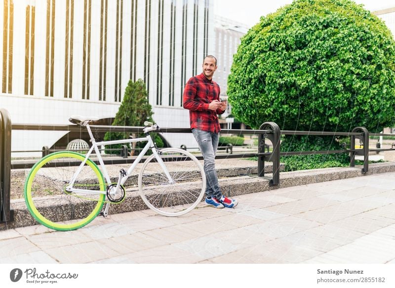 Junger Mann mit Handy und festem Fahrrad. Mobile Fixie Telefon Schickimicki Lifestyle stehen Fahrradfahren Großstadt Gebäude Solarzelle Stadt Mensch