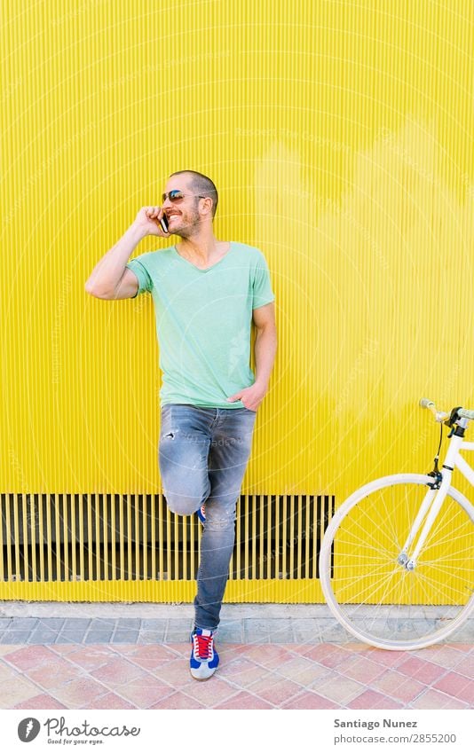 Gutaussehender junger Mann mit Handy und festem Fahrrad. Mobile Fixie Telefon Schickimicki Lifestyle stehen Fahrradfahren Großstadt Solarzelle Stadt Mensch