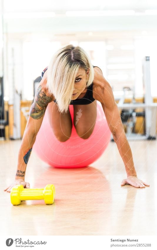 Schöne Frau, die Übungen im Fitnessstudio mit Fitnessball macht. Sporthalle Training schieben Blick Liegestütze üben Jugendliche Körper schön nach oben Ball