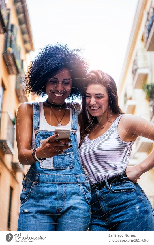 Schöne Frauen, die ein Handy auf der Straße benutzen. Freundschaft Jugendliche Glück Sommer Mensch Freude Mobile PDA Telefon Solarzelle benutzend Mitteilung