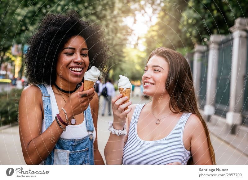 Schöne Frauen essen ein Eis auf der Straße. Freundschaft Jugendliche Afro-Look Speiseeis Kornett Verkostung Essen Creme Glück Sommer Porträt Mensch Freude