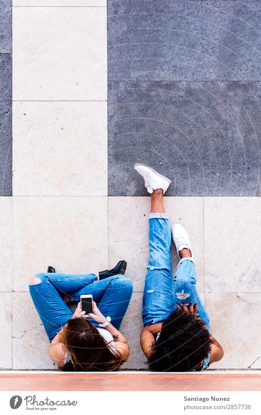 Schöne Frauen, die ein Handy auf der Straße benutzen. Freundschaft Jugendliche Glück Sommer Mensch Freude Mobile PDA Telefon Solarzelle benutzend Mitteilung