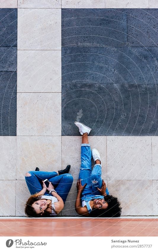 Schöne Frauen haben Spaß auf der Straße. Freundschaft Jugendliche Glück Sommer Mensch Freude Mobile PDA Telefon Solarzelle benutzend Mitteilung Texten Mädchen